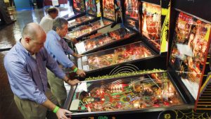 DANIA, FL - FEBRUARY 10: Barry Kowitt (L) and others play pinball machines setup during The Florida Arcade & Pinball Expo at the Dania Jai-Alai Sports Entertainment Complex on February 10, 2011 in Dania, Florida. The expo which lasts until February 13, features about 400 pinball games from the 1950s to the present. (Photo by Joe Raedle/Getty Images)