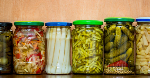 Different pickled vegetables, such as cucumbers,pepperoni, celery, white beans, in jars