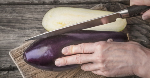 Cutting eggplants on the wooden board on the table top view